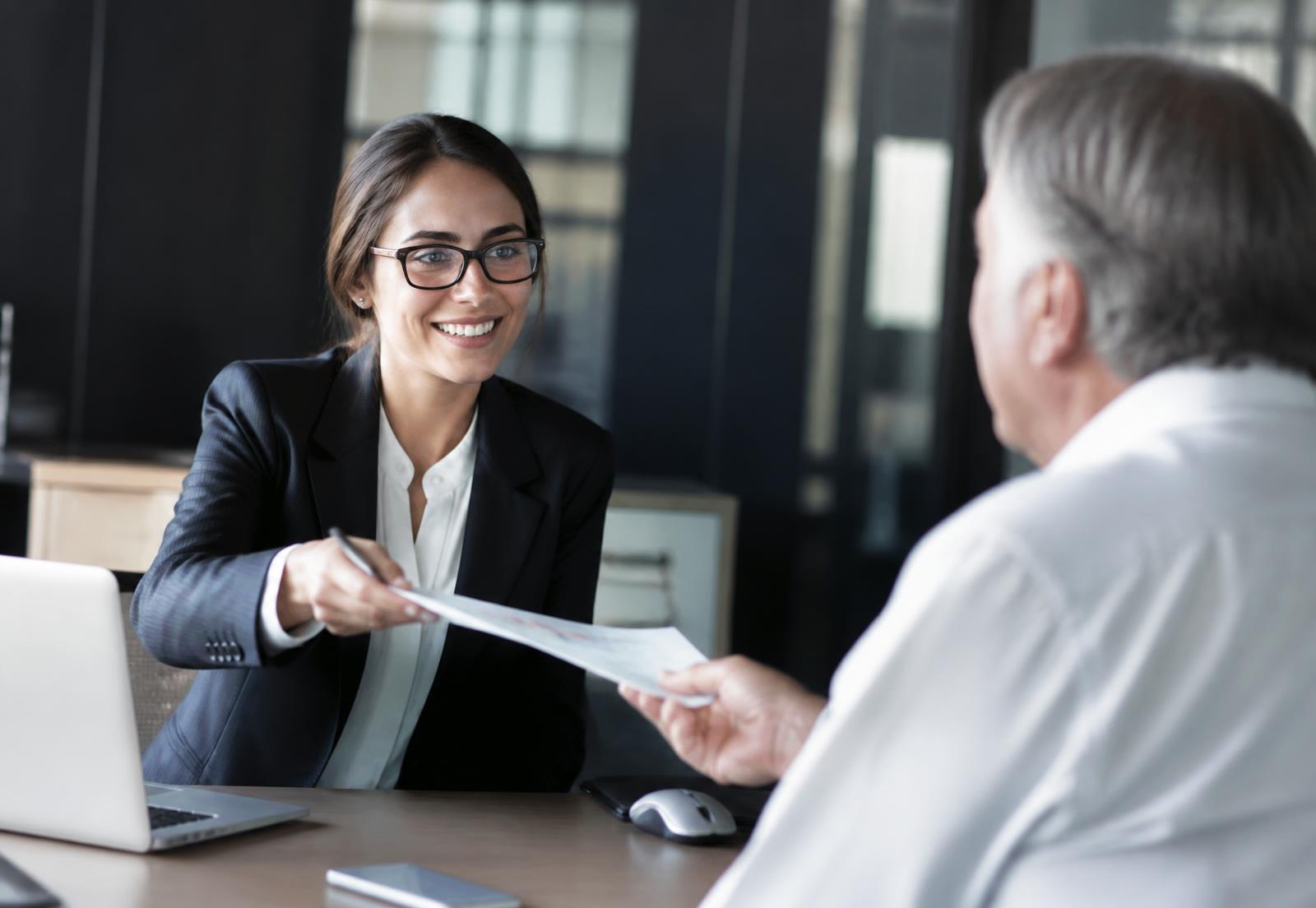 Consultora entregando documentos para o cliente em escritório